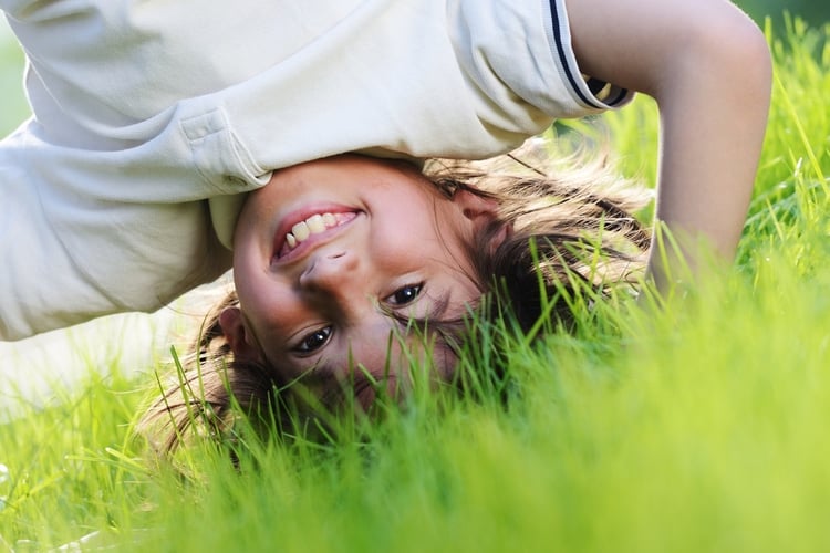 Portraits of happy kids playing upside down outdoors in summer park walking on hands