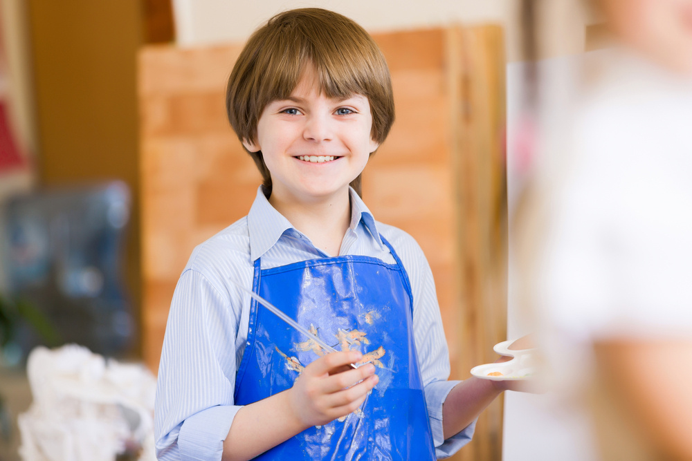 Image of little cute boy painting pictures at kindergarten